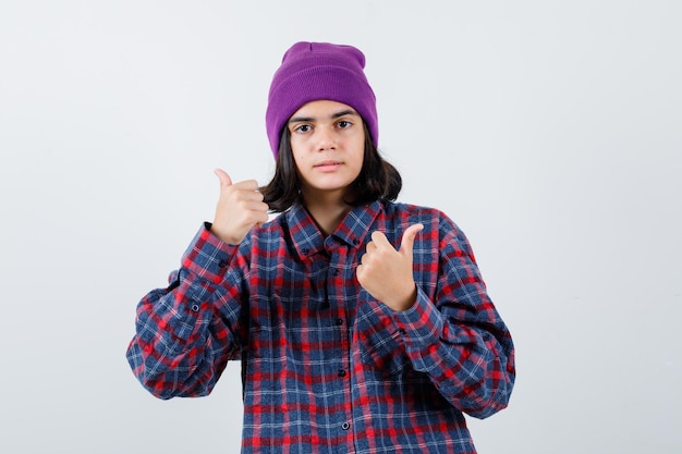 Teen femme en chemise à carreaux et bonnet gesticulant isolé