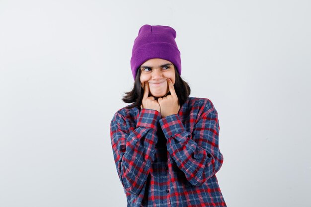 Teen femme en chemise à carreaux et bonnet gesticulant isolé