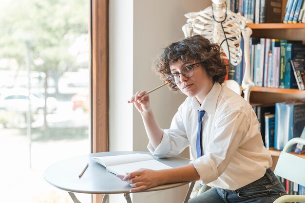 Teen fille assise près de la fenêtre dans la bibliothèque