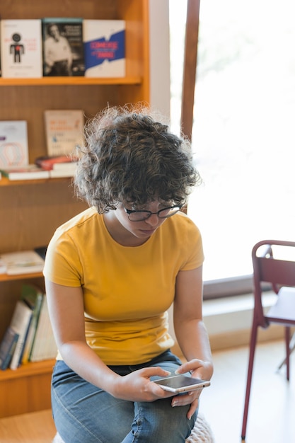 Teen girl à l&#39;aide de smartphone dans la bibliothèque