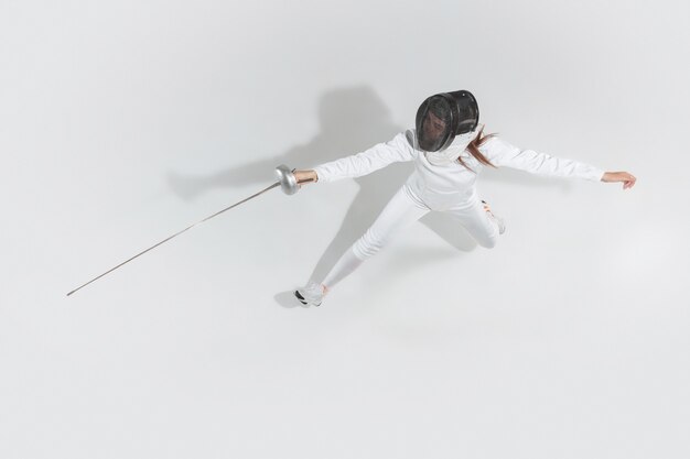 Teen girl en costume d'escrime avec l'épée à la main isolé sur fond blanc, vue du dessus