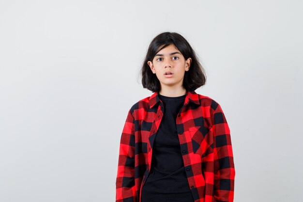 Teen girl in t-shirt, chemise à carreaux et à la perplexité, vue de face.