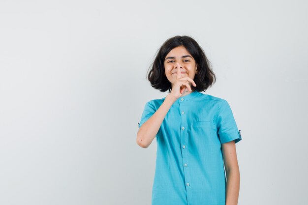 Teen girl montrant le geste de silence en chemise bleue