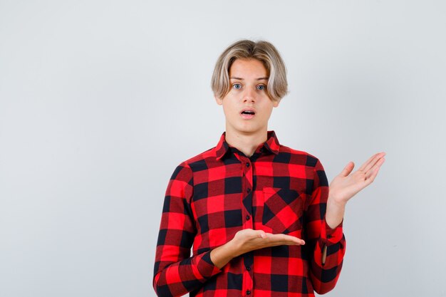 Teen mâle blond en chemise décontractée à la pensive, vue de face.