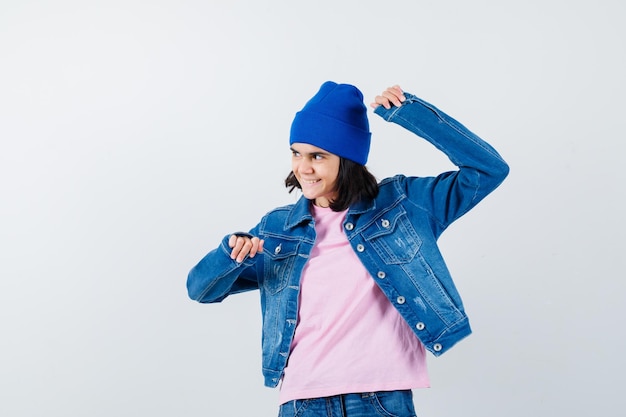 Teen woman in pink t-shirt veste en jean et bonnet montrant le geste du gagnant