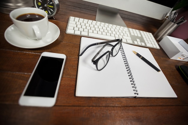 Téléphone portable avec du café noir et des lunettes