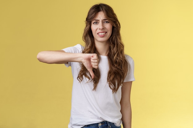 Tellement boiteux vous perdant. Ignorant snob belle femme donner son propre jugement opinion négative en désaccord grimaçant grincer des dents n'aime pas montrer le pouce vers le bas déçu fond jaune peu impressionné