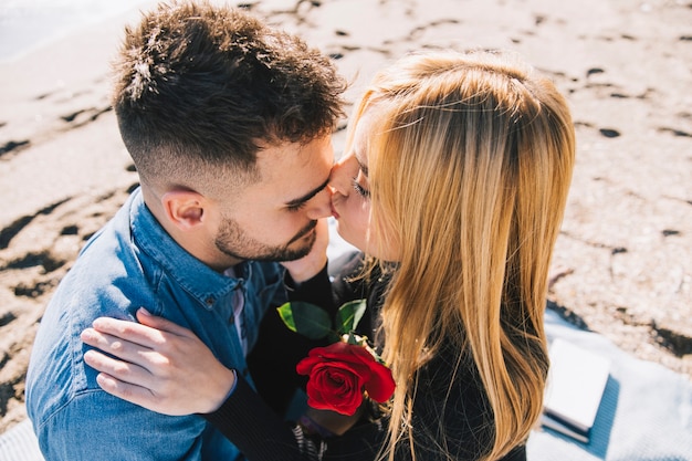 Photo gratuite tendre femme embrassant un homme assis sur la plage