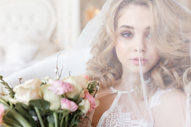 Tendre portrait d&#39;une belle mariée sous un voile tenant le bouquet.