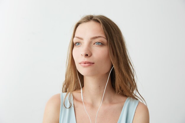 Tendre rêveuse jeune jolie fille rêvant d'écouter de la musique en streaming dans les écouteurs.