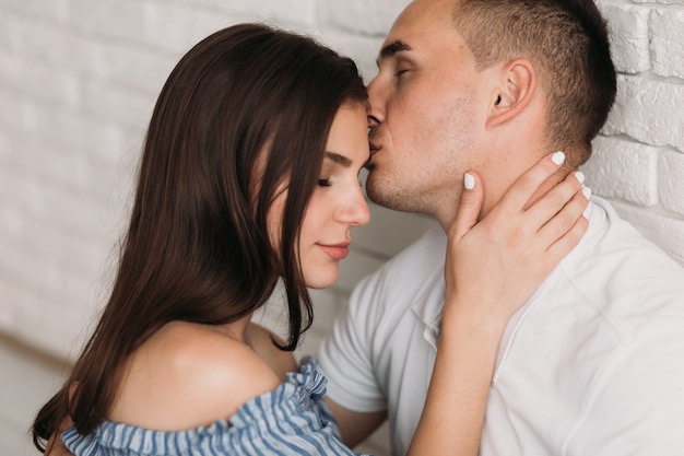 Tendres câlins et bisous d&#39;un homme et d&#39;une femme reposant sur le sol dans une pièce blanche