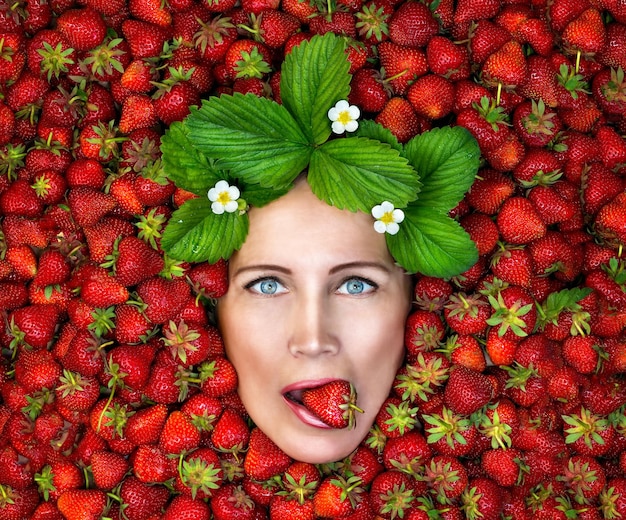Tentation rouge-mûre. un portrait d'une femme sexy nue tenant une fraise rouge-mûre dans sa bouche.