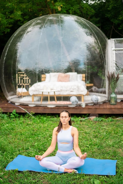 Photo gratuite tente à bulles transparente et femme faisant du yoga au glamping