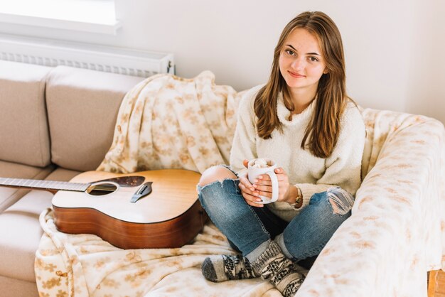 Tenue femme, tasse, près, guitare, sur, sofa