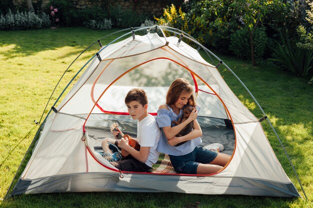 Tenue fille, petit chien, séance, à, son, frère, dans, tente camp, dans, parc