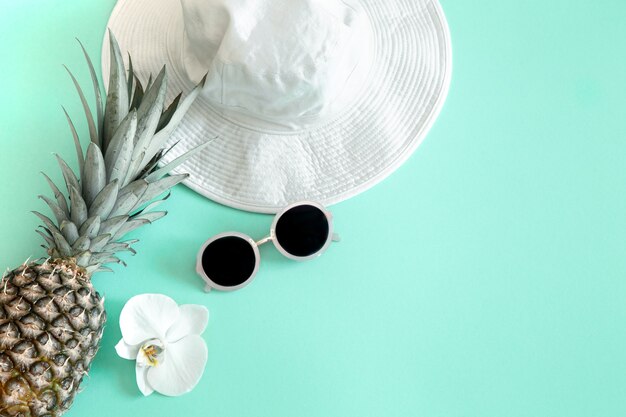 Tenue de mode féminine estivale colorée à plat.Chapeau pour femme élégant blanc avec lunettes de soleil et ananas frais. Mode d'été ou concept de voyage de vacances