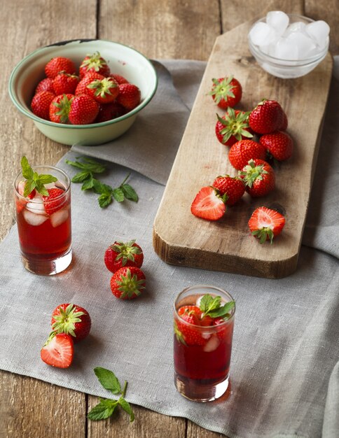 Tequilas aux fraises près de fraises hachées sur une planche à découper