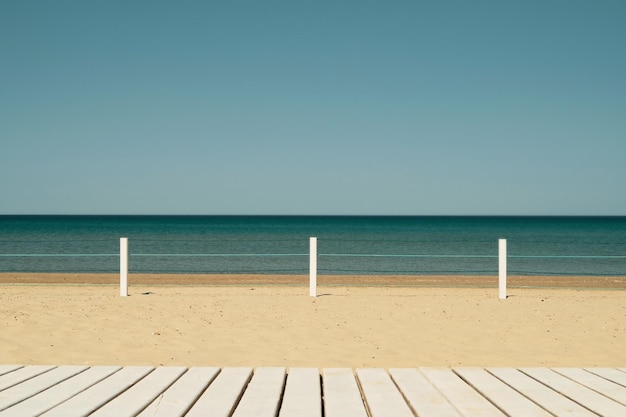 Terrasse en bois sur une plage de sable fin dans une ville de villégiature lumière aérée sentir bleu ciel sans nuages L'idée d'une plage de vacances en mer une idée pour une bannière
