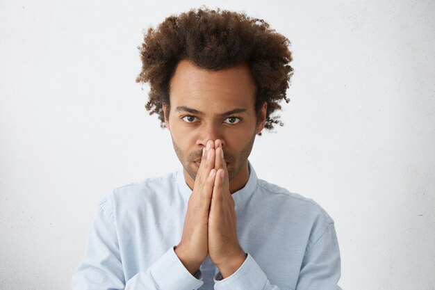 Tête d'un employé afro-américain attrayant avec une coiffure funky se tenant la main sur son visage