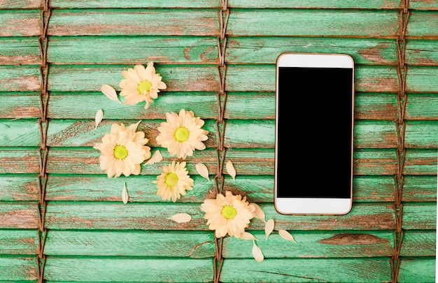 Tête de fleur couleur pêche et téléphone portable sur fond de volet en bois