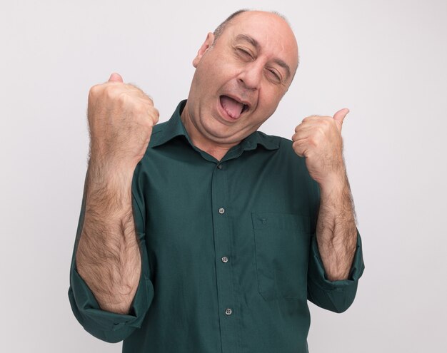 Tête inclinable joyeuse avec les yeux fermés homme d'âge moyen portant un t-shirt vert montrant un geste oui isolé sur un mur blanc