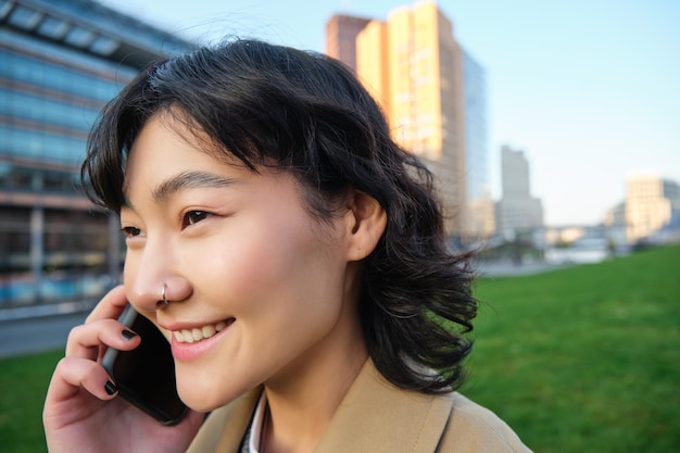 Photo gratuite tête de jeune femme coréenne marche sur les pourparlers de rue sur téléphone mobile a une conversation téléphonique stan