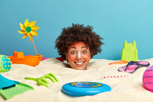 Tête De Jeune Femme Avec Crème Solaire Sur Le Visage Entouré D'accessoires De Plage