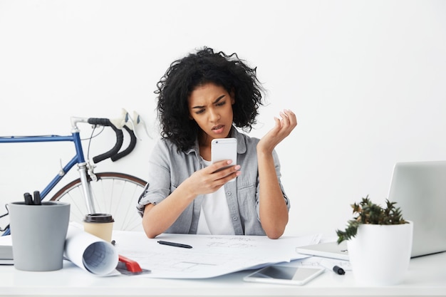 Photo gratuite tête de jeune femme métisse inquiète ou frustrée architecte lecture message texte urgent