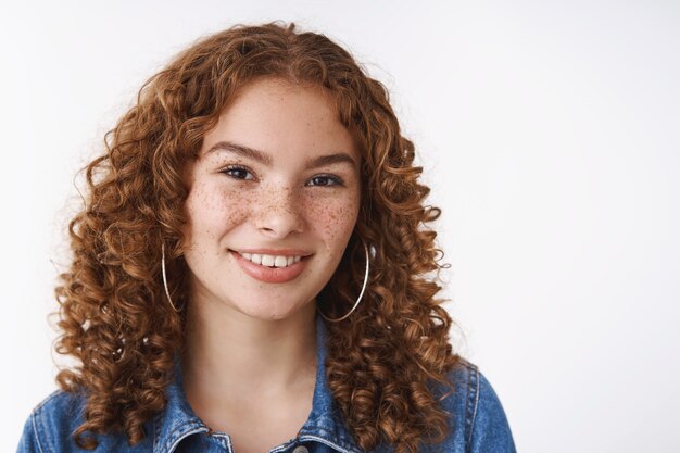 Tête mignonne charismatique sympathique souriante heureuse rousse bouclée fille aux taches de rousseur peau sujette à l'acné bouton front souriant profitant du jour du printemps, apparence indifférente, promouvoir l'amour de soi