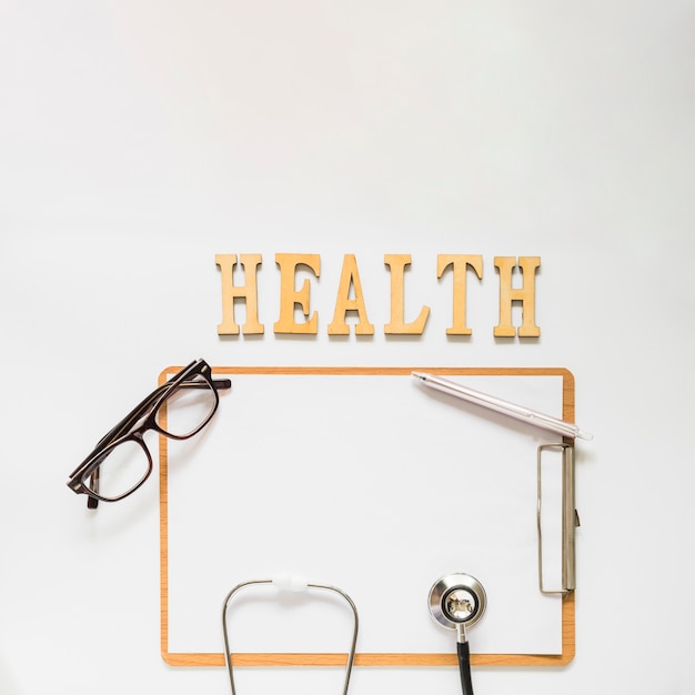 Texte de santé près du presse-papiers avec des lunettes; stéthoscope et stylo sur fond blanc