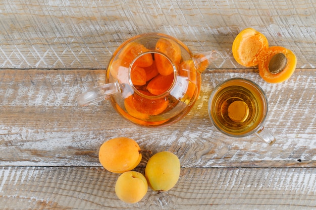 Thé à l'abricot dans la théière et tasse en verre avec vue de dessus abricots sur une table en bois