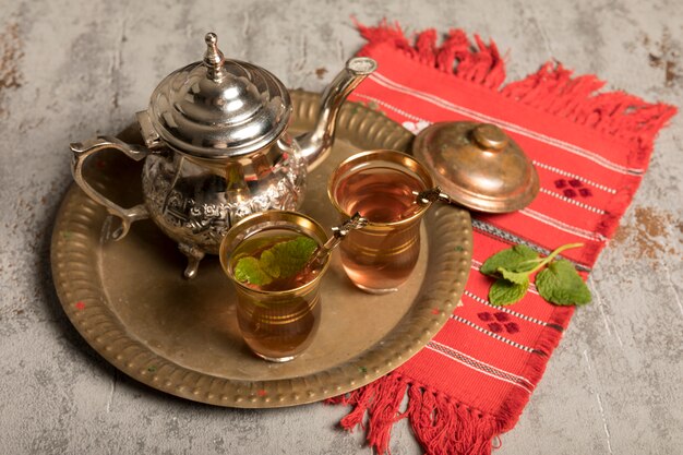 Thé arabe dans des verres avec une théière sur un drap rouge