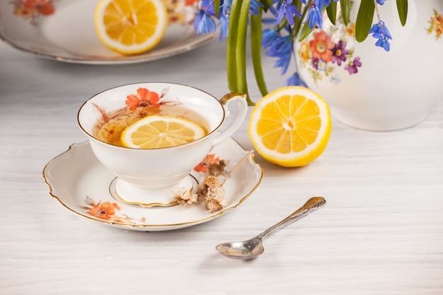 Thé au citron et bouquet de primevères bleues sur la table