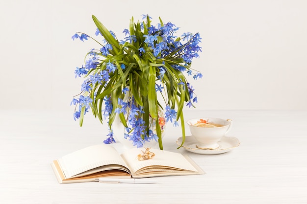 Thé au citron et bouquet de primevères bleues sur la table