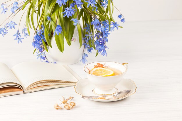 Thé au citron et bouquet de primevères bleues sur la table