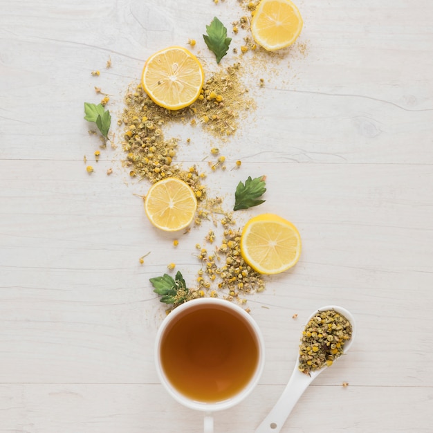 Thé au citron avec des fleurs de chrysanthème chinois séchées et des tranches de citron sur une table en bois