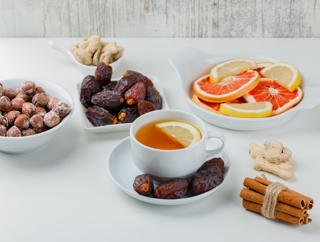 Thé au gingembre, bâtons de cannelle, agrumes, dattes, noix dans une tasse