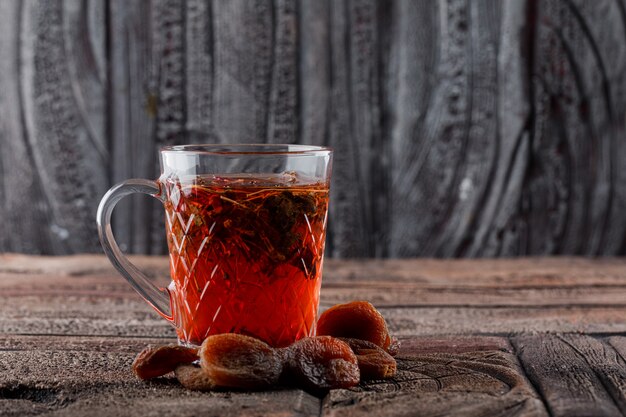 Thé aux fruits secs dans une tasse sur carrelage en pierre et surface en bois