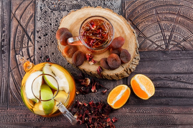 Thé aux fruits secs, herbes, fruits infusés d'eau, orange, bois dans une tasse sur la surface de carreaux de pierre, vue de dessus