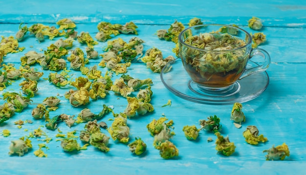 Thé aux herbes séchées dans une tasse en verre sur bois bleu, high angle view.