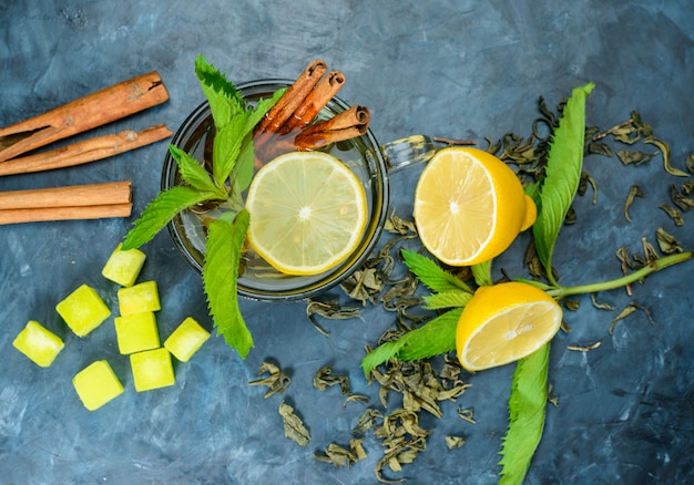 Thé dans une tasse de citron, menthe, bâtons de cannelle, cubes de sucre vue de dessus sur une surface bleue