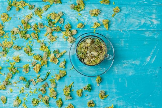 Thé dans une tasse en verre avec des herbes séchées Vue de dessus sur bois bleu