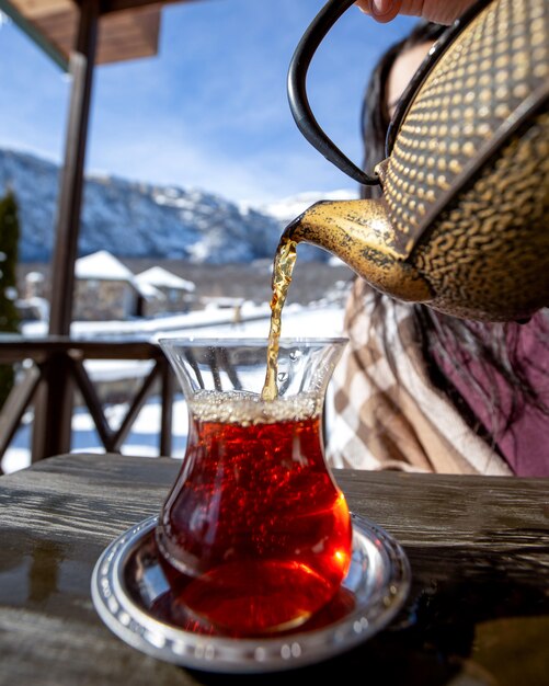 thé une femme versant du thé noir sur fond de montagne