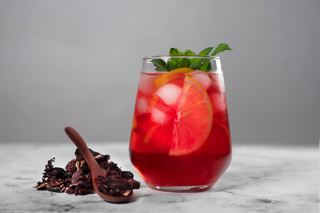 Thé glacé à l'hibiscus rafraîchissant dans un récipient en verre transparent