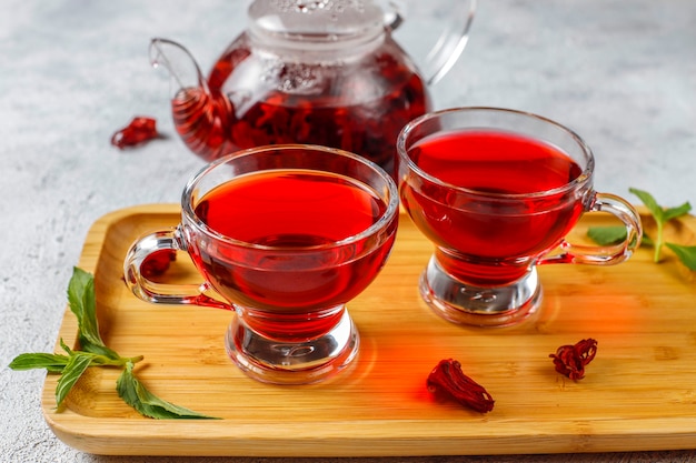 Thé à l'hibiscus chaud dans une tasse en verre et théière en verre.