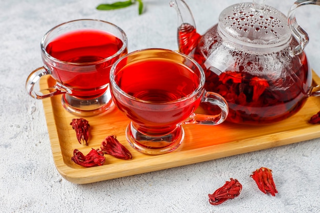 Thé à l'hibiscus chaud dans une tasse en verre et théière en verre.