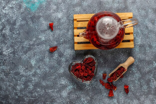 Thé à l'hibiscus chaud dans une tasse en verre et théière en verre.