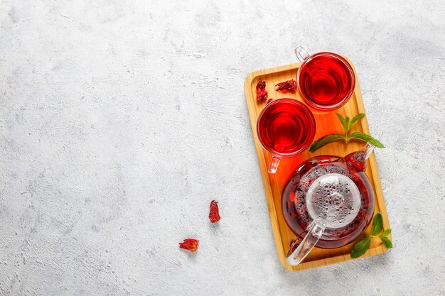 Thé à l'hibiscus chaud dans une tasse en verre et théière en verre.