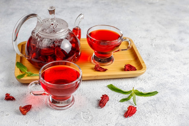 Thé à l'hibiscus chaud dans une tasse en verre et théière en verre.