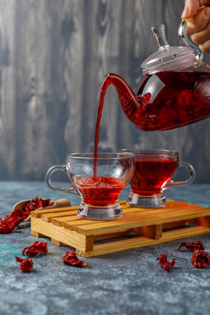 Thé à l'hibiscus chaud dans une tasse en verre et théière en verre.